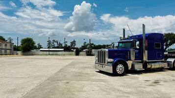 A large, empty parking lot with a blue semi-truck parked in the foreground.