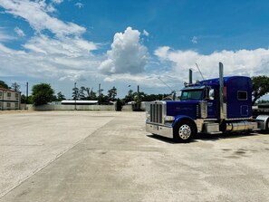 A large, empty parking lot with a blue semi-truck parked in the foreground.
