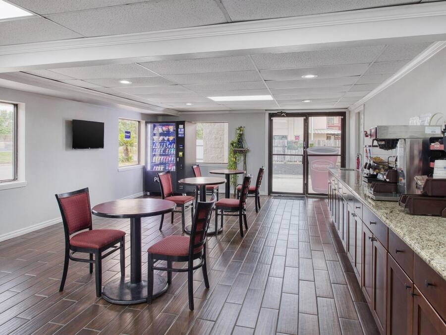 Un restaurante con barra, zona de estar y un televisor en la pared.