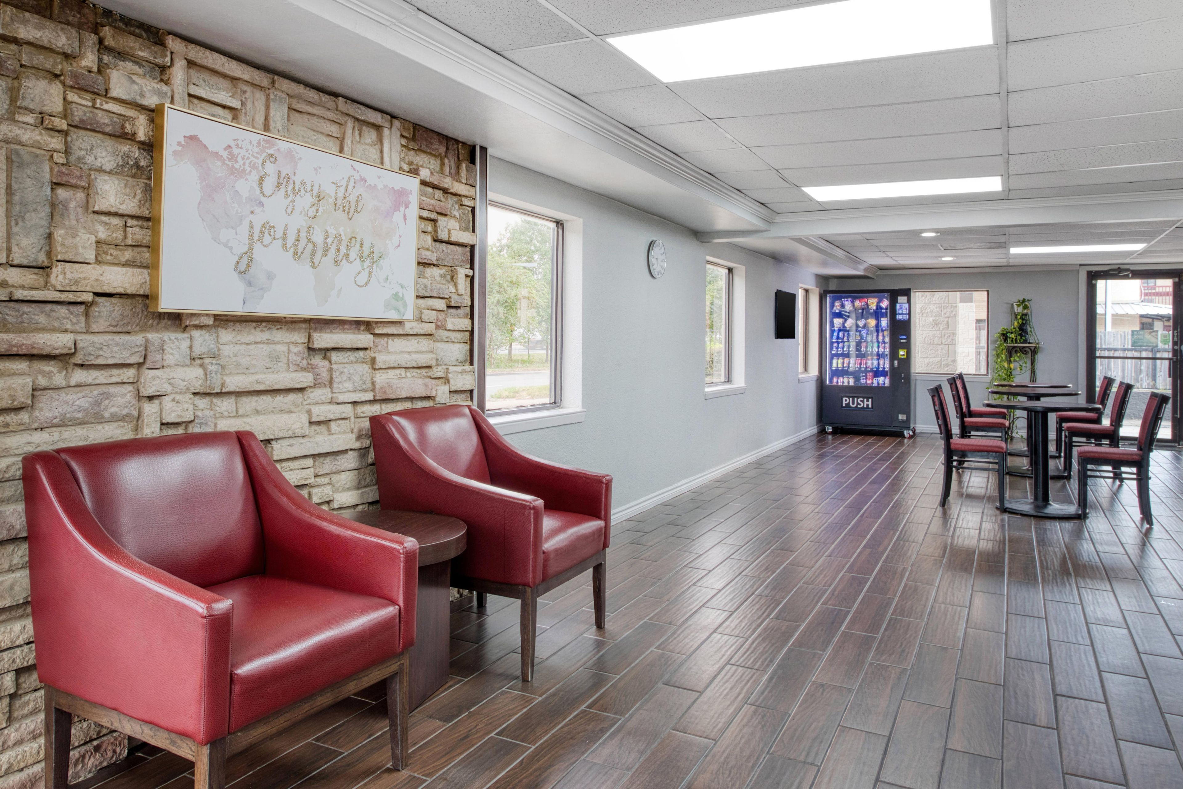 A reception area with a stone wall, red leather chairs, a clock, and a vending machine.