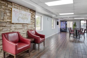 A reception area with a stone wall, red leather chairs, a clock, and a vending machine. - SureStay by Best Western Channelview Houston East (Channelview)