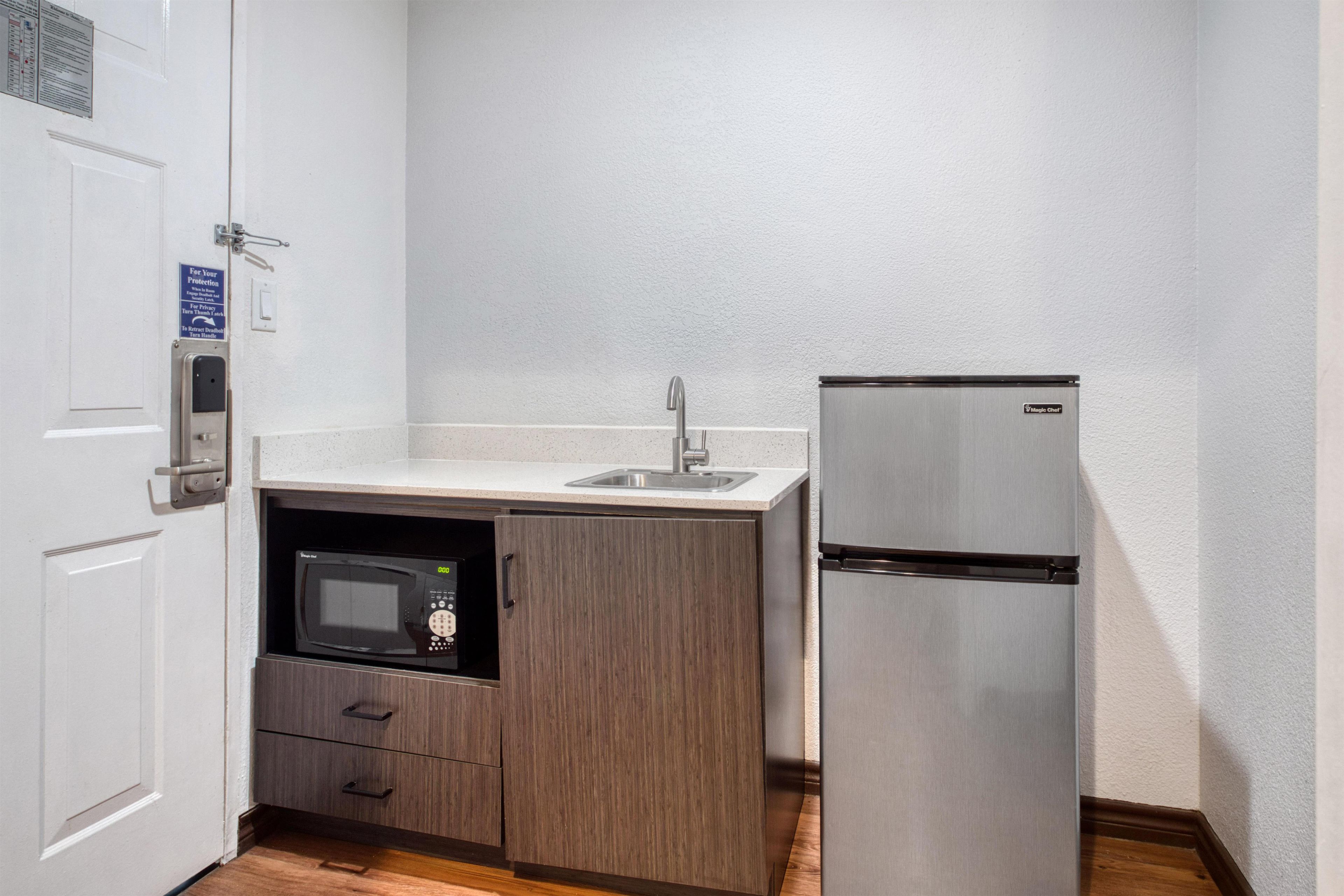A compact kitchen with a microwave, a refrigerator, and a sink.