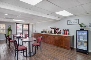 A café with wooden flooring, a counter with coffee machines, and a refrigerator with beverages. - SureStay by Best Western Channelview Houston East (Channelview)