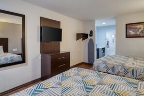 A hotel room with a bed, a dresser, a television, and a bathroom visible through an open door. - SureStay by Best Western Channelview Houston East (Channelview)