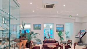 A reception area with a glass display case, leather sofas, a coffee table, and potted plants. - Hôtel Esprit d'Azur (Nice)