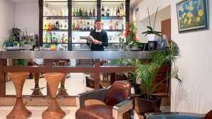A bar area with a bartender, shelves of liquor, and seating with potted plants. - Hôtel Esprit d'Azur (Nice)