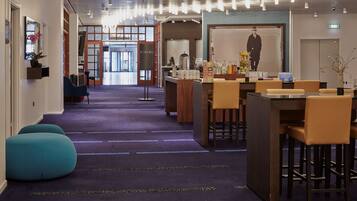 A hotel lobby with a reception desk, seating area, and a large poster on the wall.