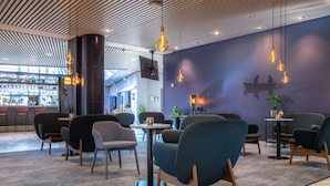 Un área de lounge moderna con asientos y una barra al fondo.
