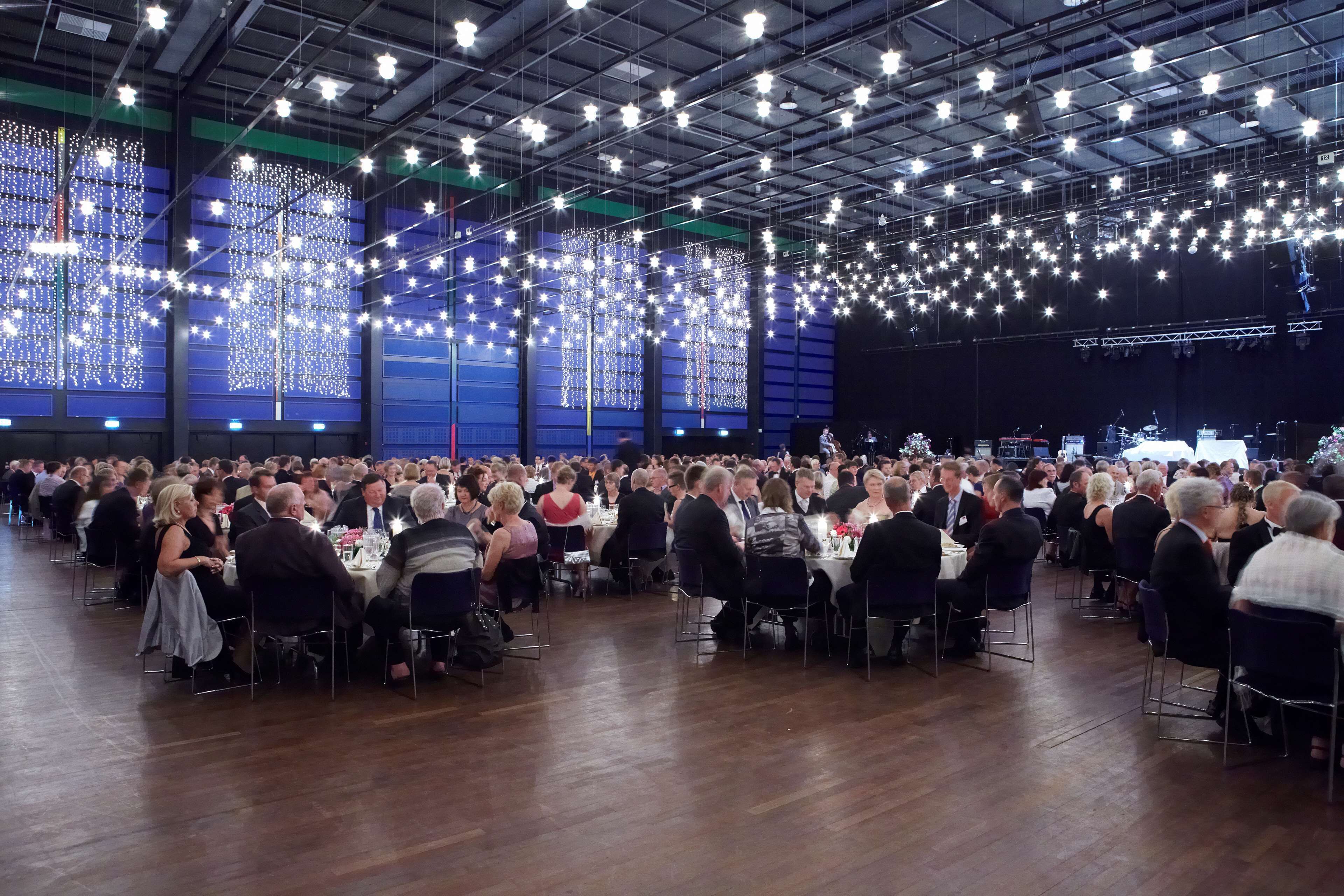 Un gran evento en interiores con mesas y sillas dispuestas para los asistentes.