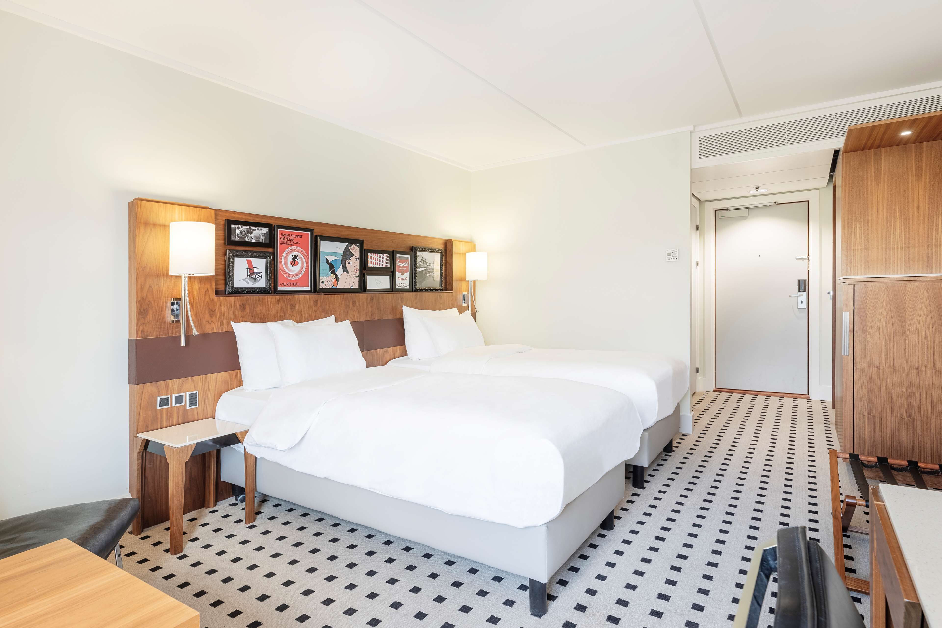 A hotel room with a large bed, bedside tables, a desk, and a wardrobe.