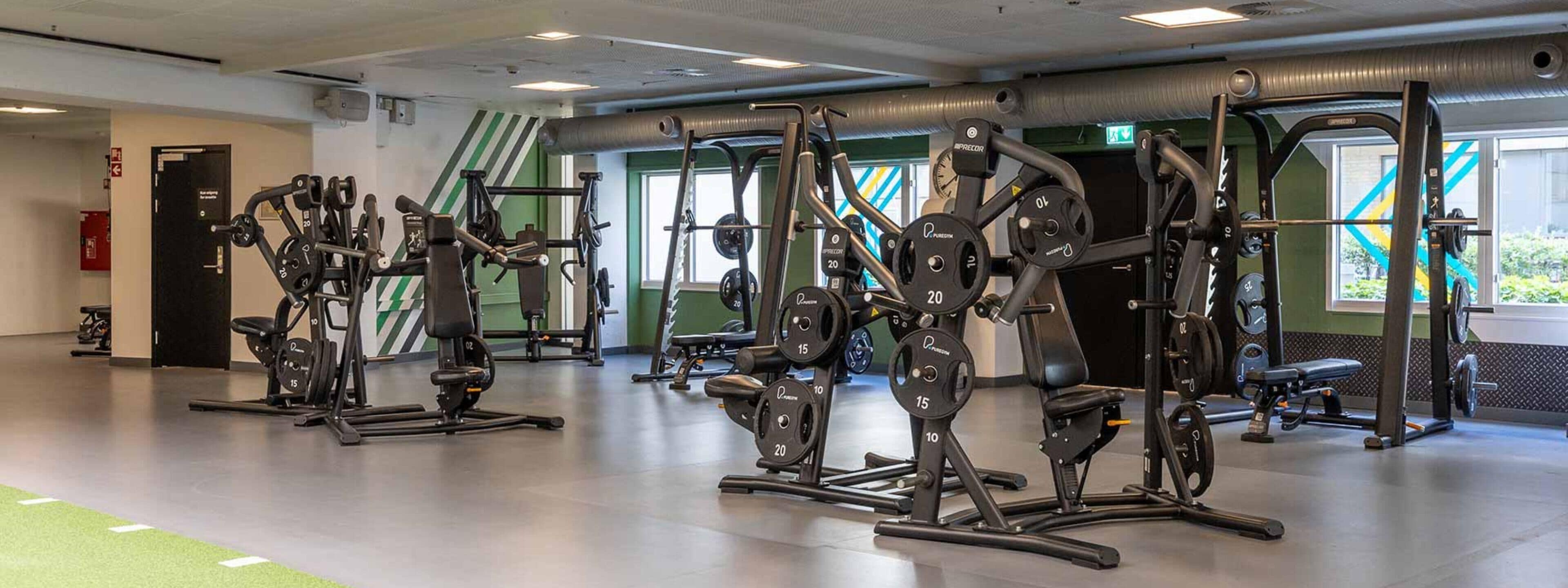 Une salle de sport équipée de divers appareils d’exercice, de piles de poids et de bancs.