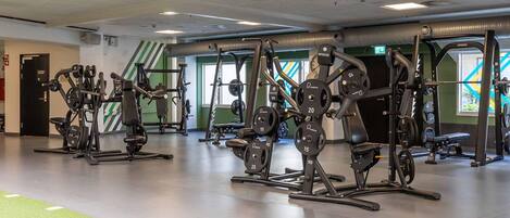 Une salle de sport équipée de divers appareils d’exercice, de piles de poids et de bancs.