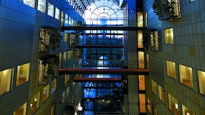 Un edificio moderno con techo de vidrio, varios pisos y escaleras visibles.
