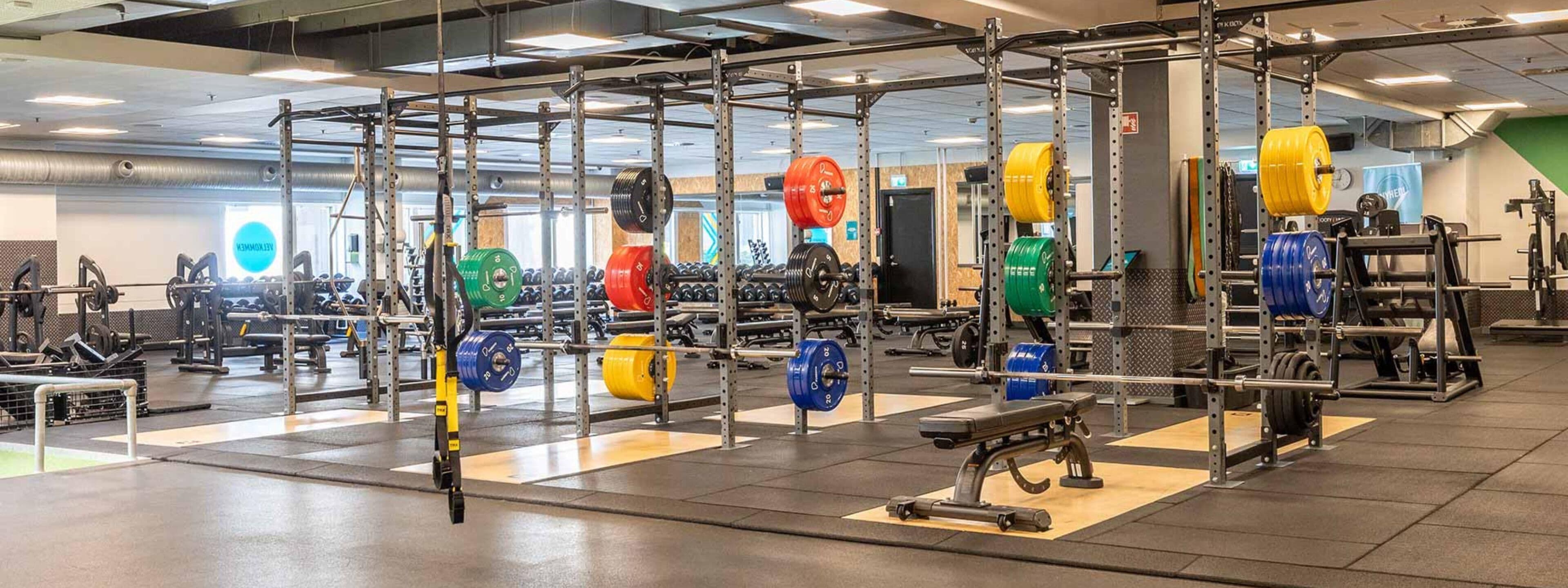A gym with various weightlifting equipment, including barbells and weight plates.