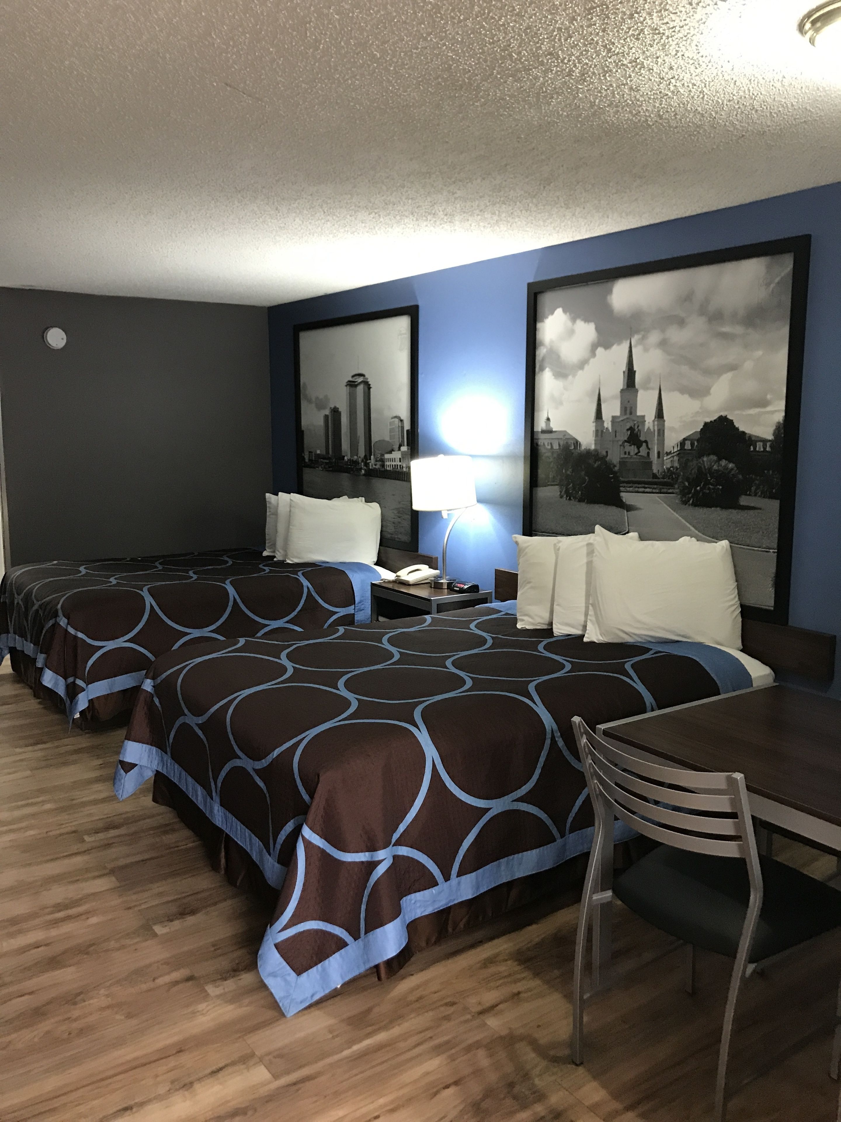 Une chambre d’hôtel avec deux lits, un bureau, une chaise et deux tableaux encadrés au mur.