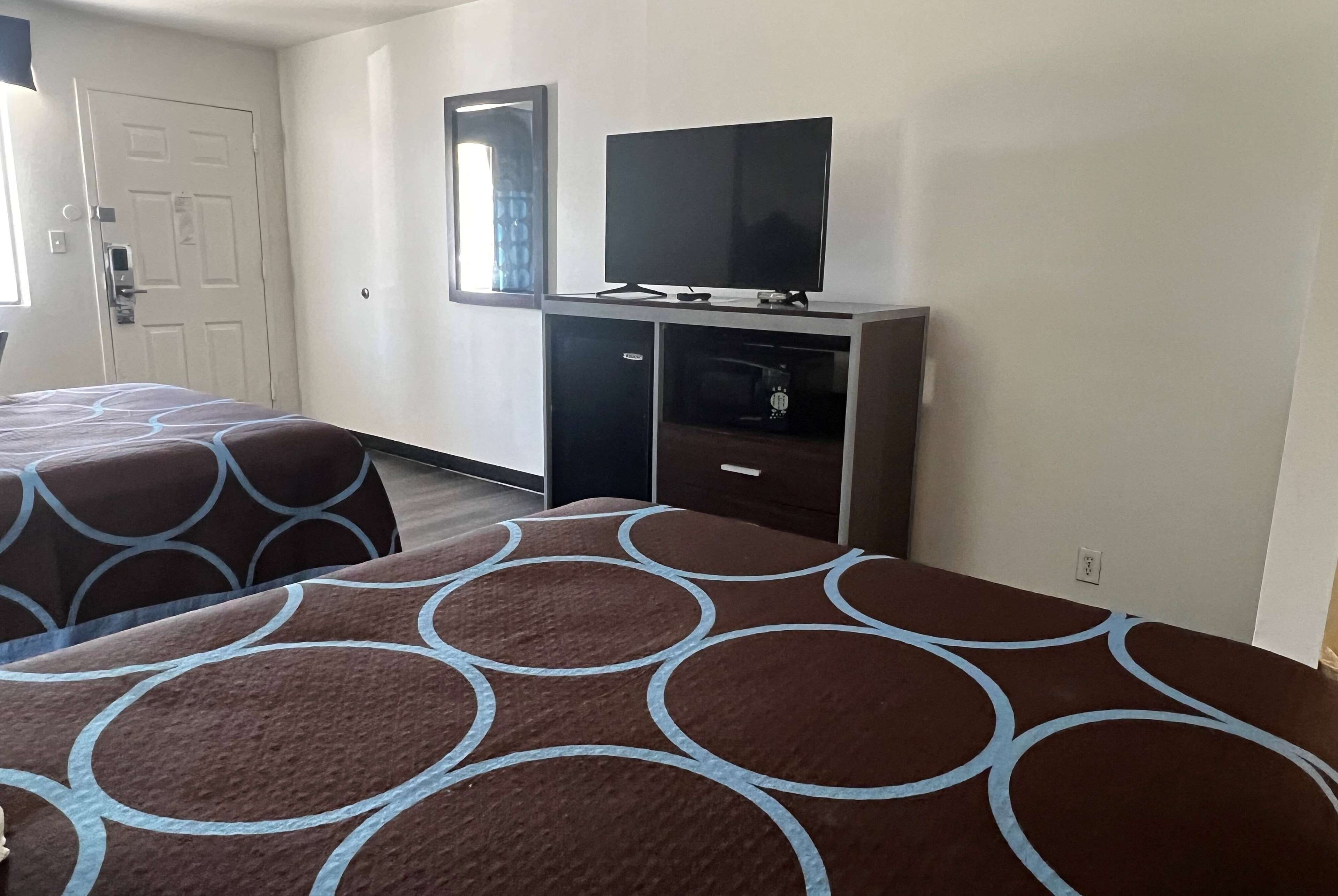A hotel room with two beds, a TV on a stand, a wardrobe, and a window.