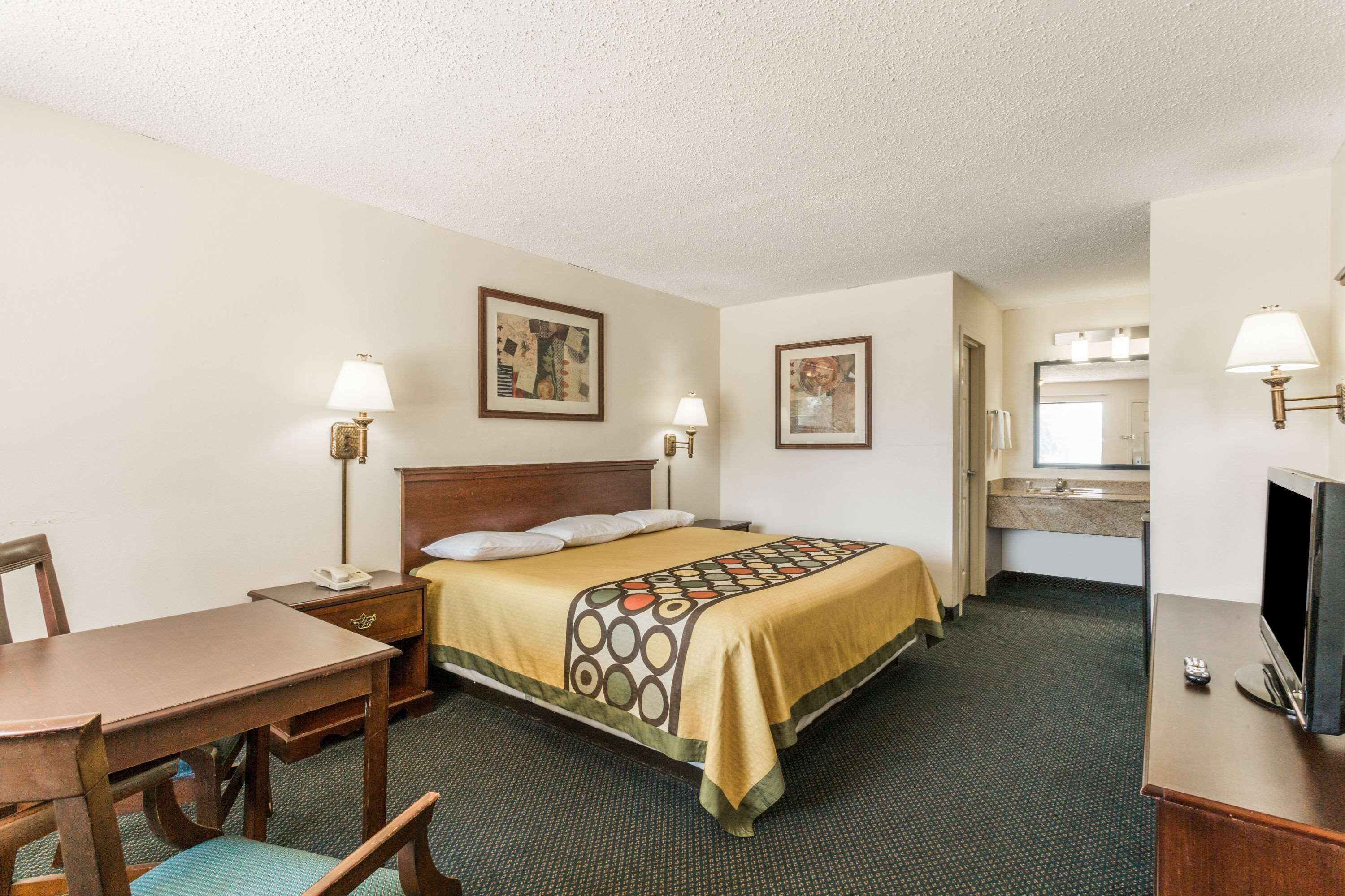 Une chambre d’hôtel comprenant un lit, un bureau, une chaise, une télévision et une salle de bain.