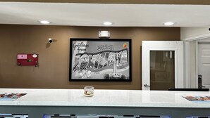 A reception area with a framed welcome sign, a fire alarm, and a modern counter design. - Super 8 by Wyndham Slidell (Slidell)