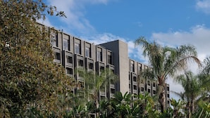 A modern building with multiple balconies and a flat roof, surrounded by lush greenery. - Knott's Hotel (Buena Park)
