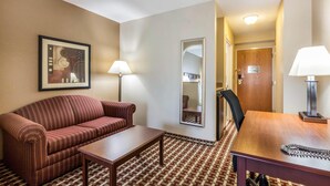 Habitació d'hotel amb un sofà estriat, una taula petita, un escriptori de fusta, dues làmpades, un mirall i un paviment amb un disseny.