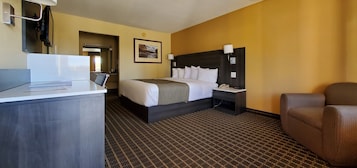 Una habitación de hotel con cama, mesita de noche, silla y escritorio con lámpara.
