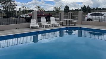 Una piscina al aire libre de temporada, sillones reclinables de piscina