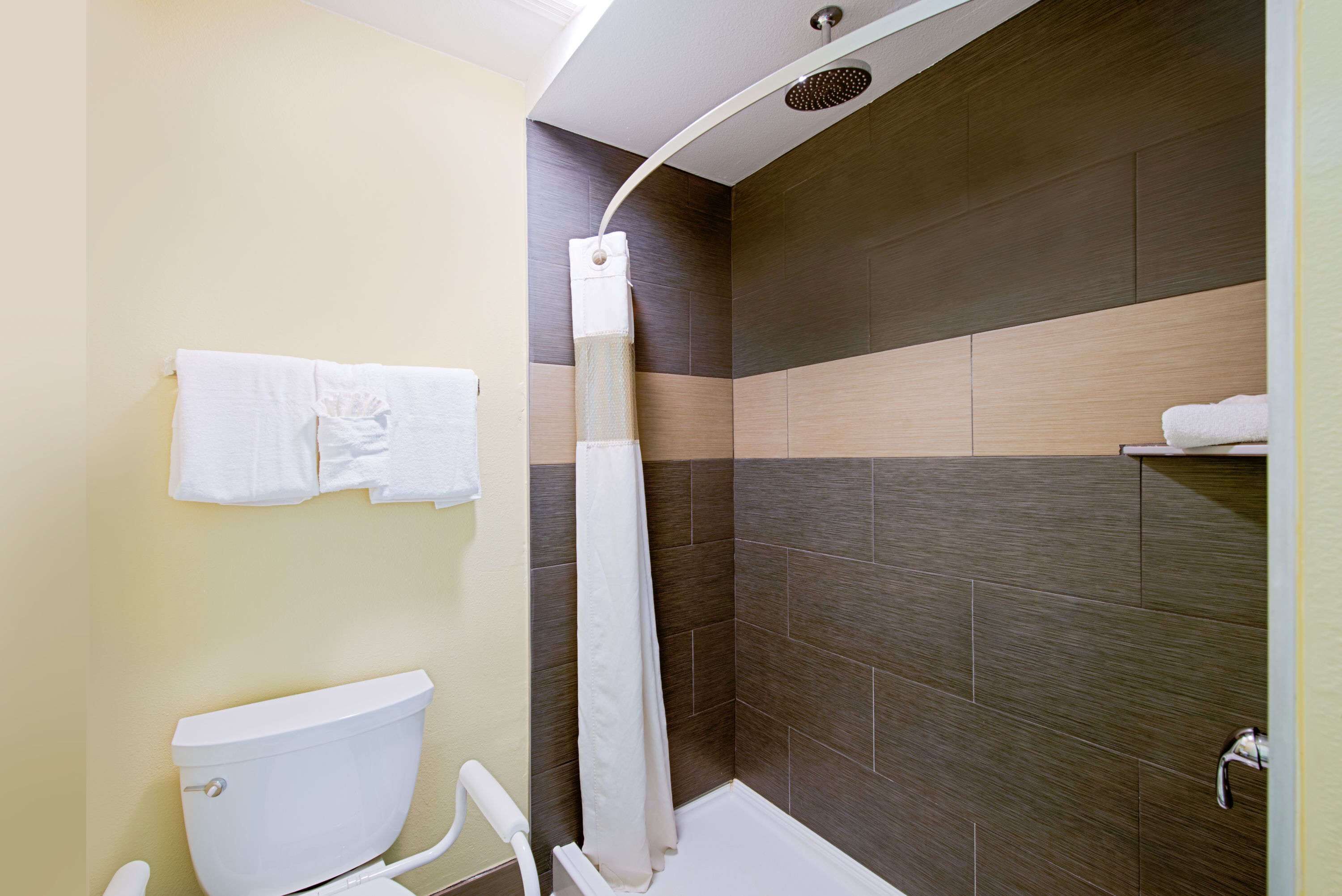 A modern bathroom with a toilet, shower, and towel rack.