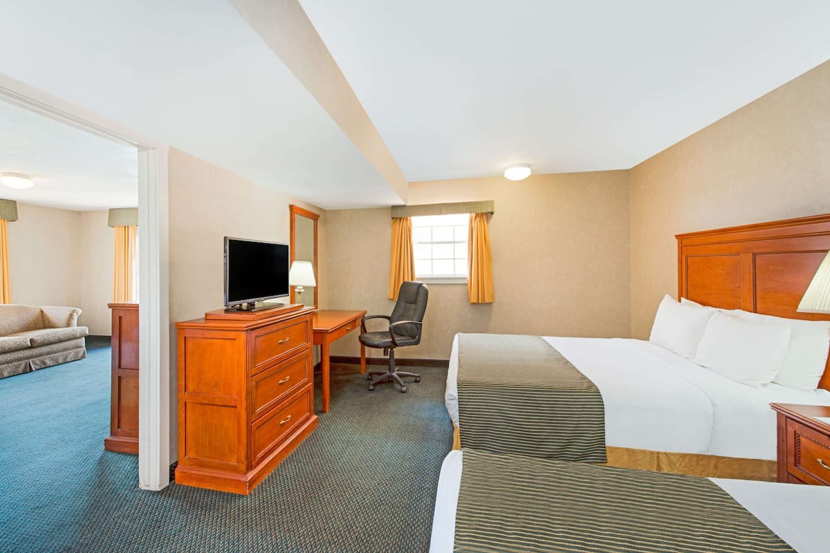 Ein Hotelzimmer mit einem Bett, einem Schreibtisch mit Stuhl, einem Fernseher und einem Sofa.