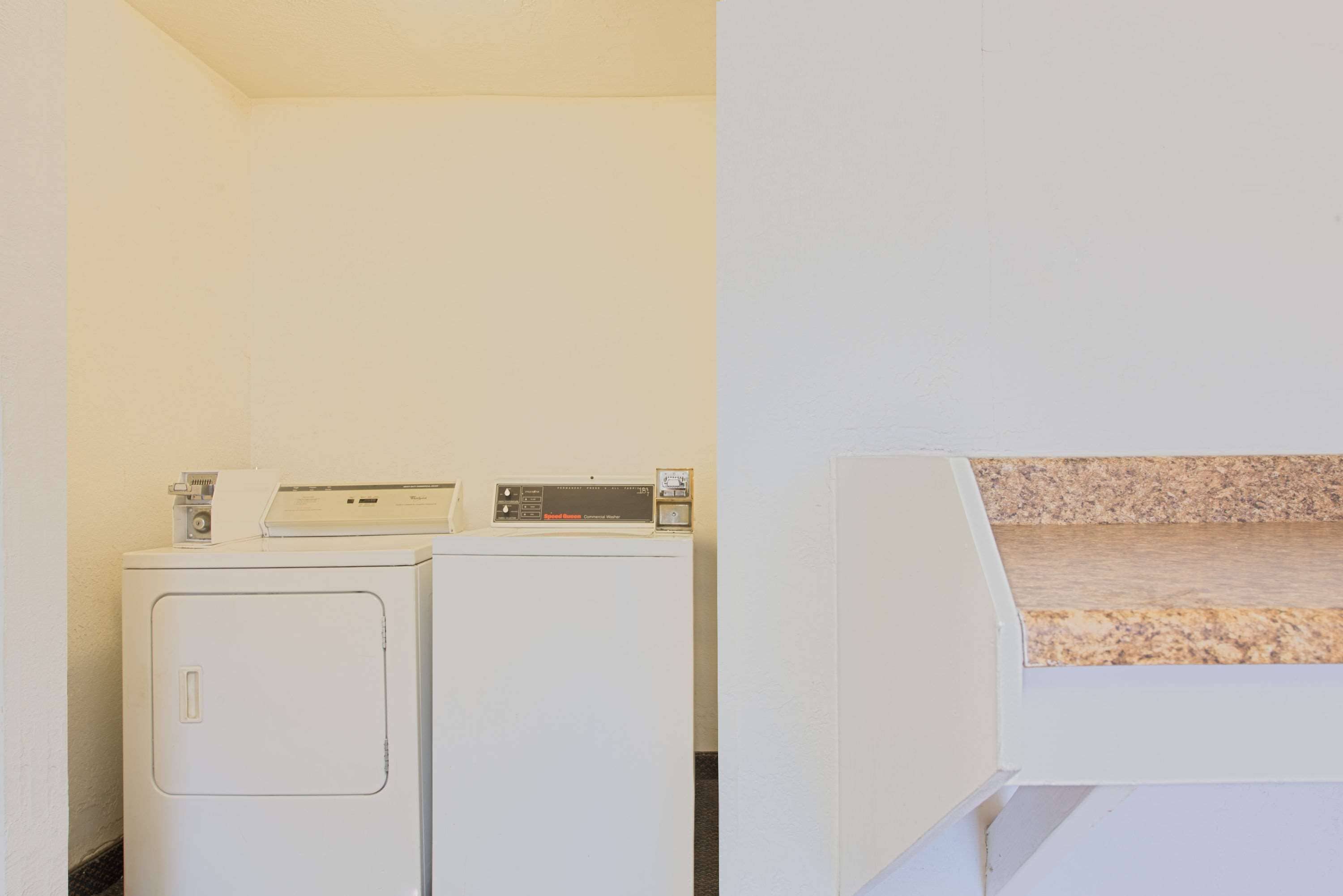 A laundry area with two white washing machines and a dryer.