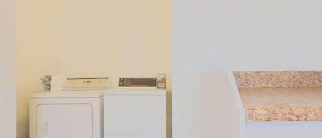 A laundry area with two white washing machines and a dryer.
