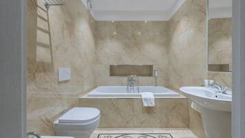 A modern bathroom with a bathtub, two sinks, and a toilet.