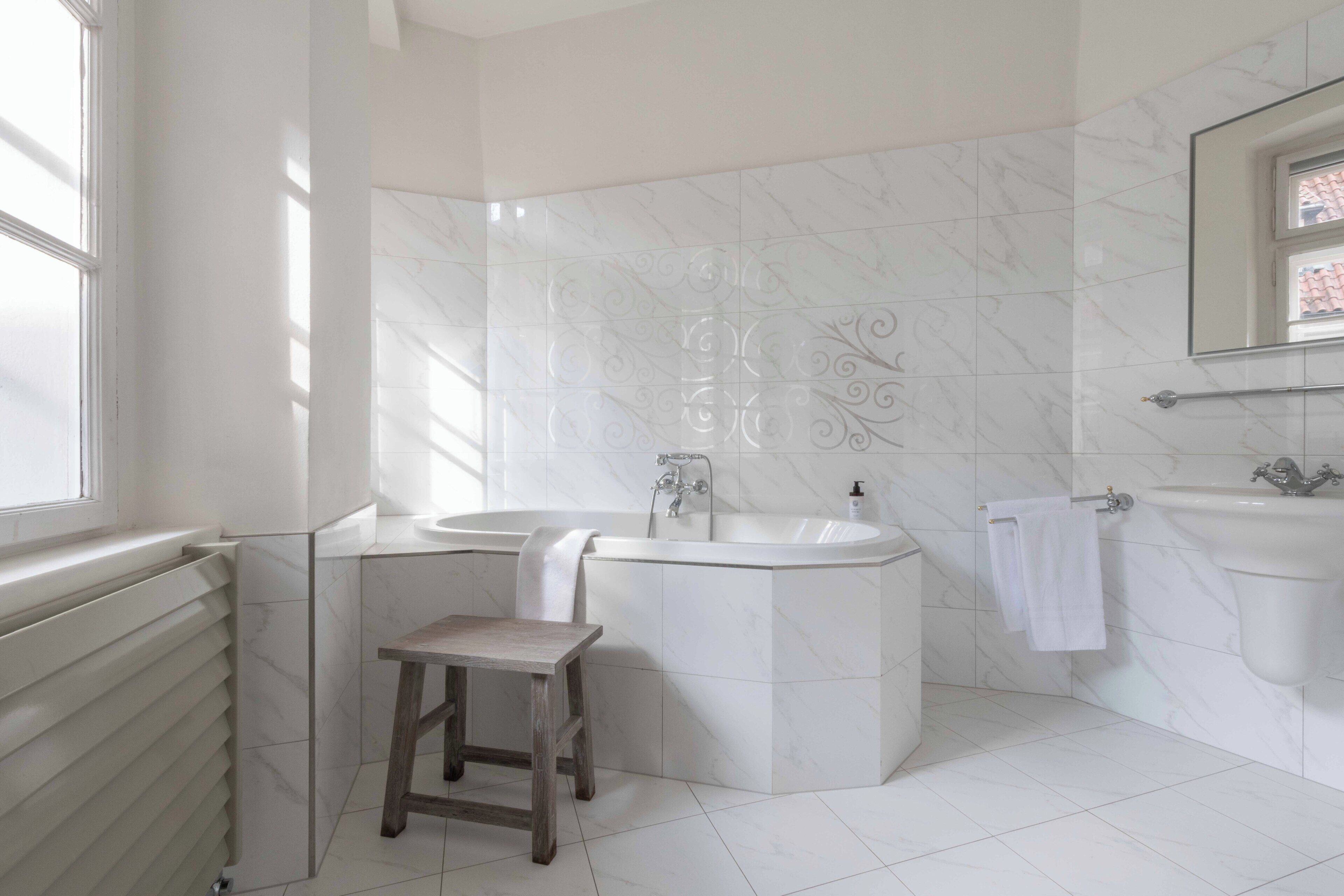 A bathroom with a bathtub, a sink, a mirror, and a radiator.