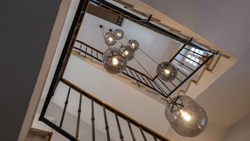 A modern interior with a staircase, a chandelier, and a large mirror.