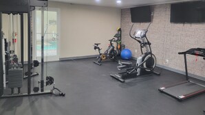 Een sportschool met trainingsapparatuur, een loopband en een hometrainer.