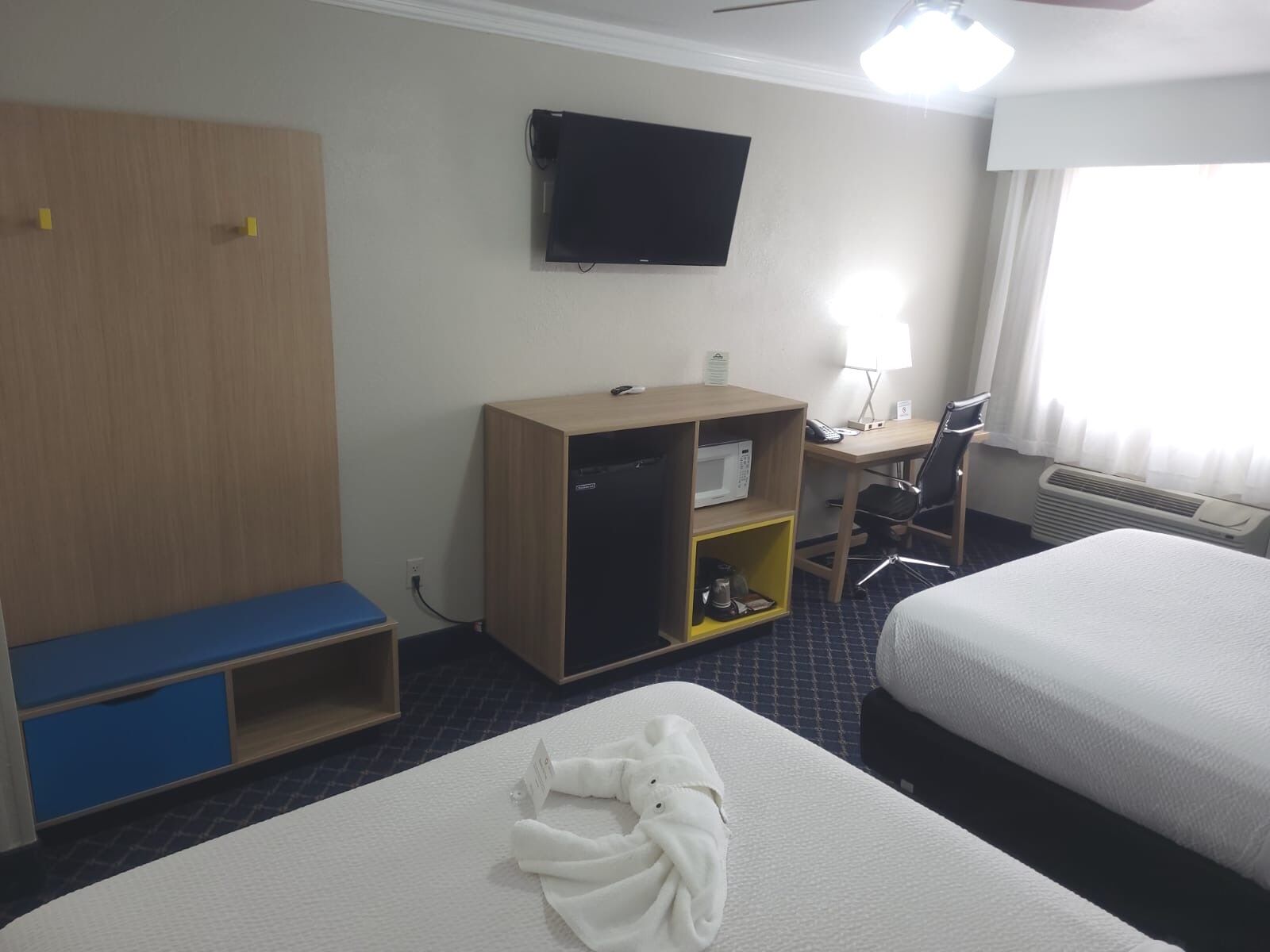Habitación de hotel con cama, escritorio con computadora, televisor, microondas y zona de estar.