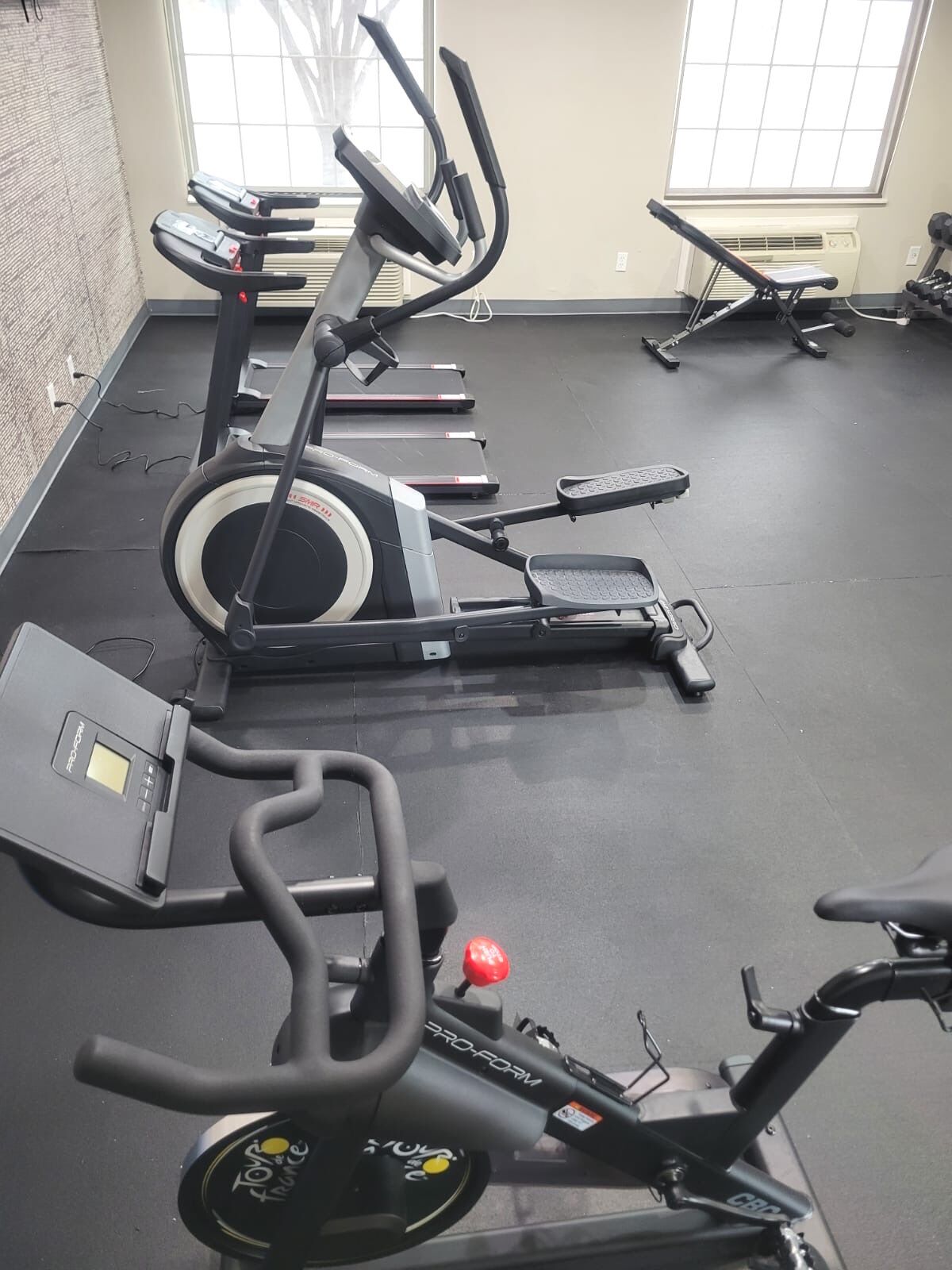 A gym with multiple cardio machines, including treadmills and an elliptical.