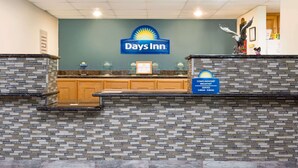 Een receptiegebied van een Days Inn met een muur van stenen tegels, een receptiebalie en een bordje voor een gratis ontbijt.