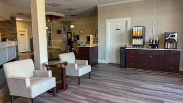 A lobby with a reception desk, seating area, and a coffee station.