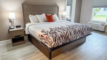 Une chambre à coucher avec un lit, une table de chevet, une lampe et une vue sur l’extérieur.