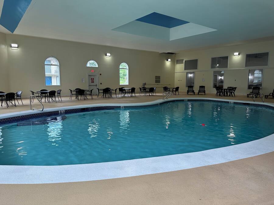 Ein Innenpool mit klarem, blauem Wasser, umgeben von schwarzen Liegestühlen und Tischen.