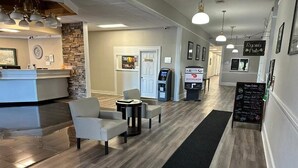 A reception area with a counter, seating, a digital kiosk, and a chalkboard with a menu. - Whaler Inn and Suites (New Bedford)