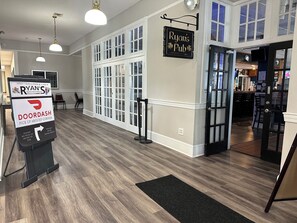 A pub interior with a sign for Ryan's Pub, a pick-up area, and a bar visible through the open door. - Whaler Inn and Suites (New Bedford)
