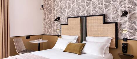 Ein Hotelzimmer mit einem Bett, einem kleinen runden Tisch, einem Sessel und einem an der Wand befestigten Telefon.
