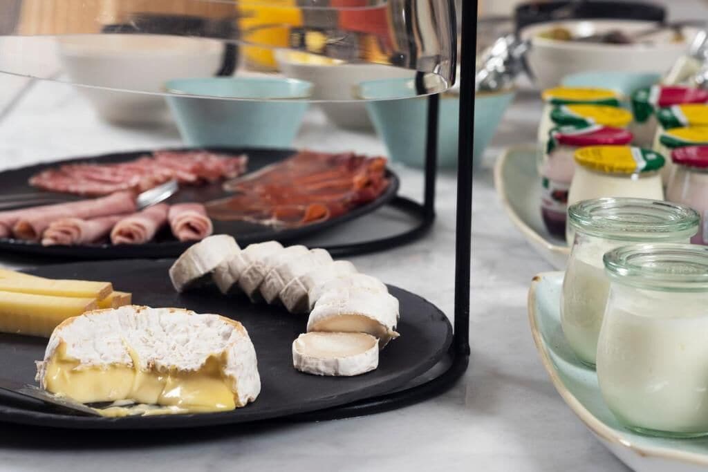A charcuterie board with various meats, cheeses, and a glass of milk.