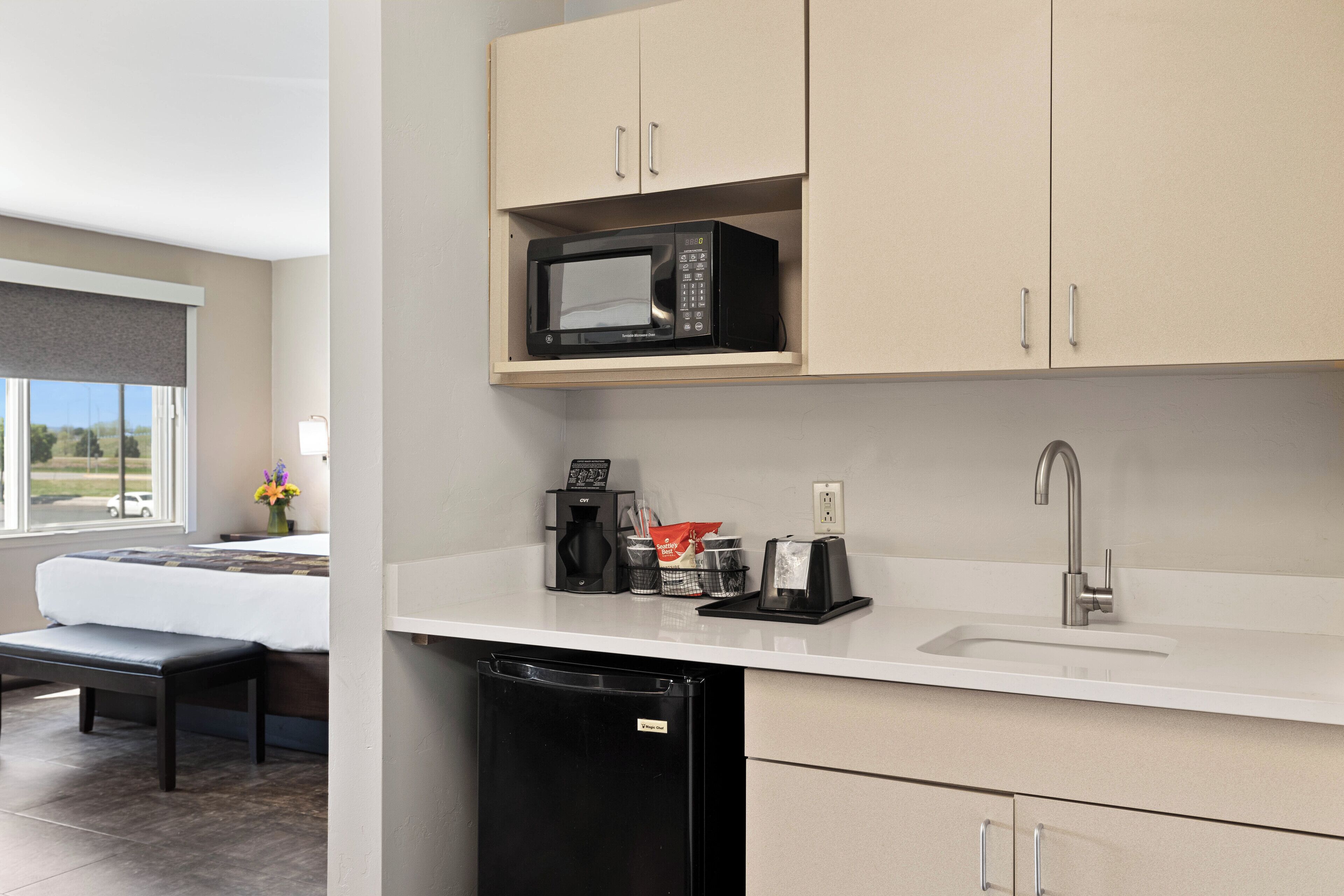 A modern kitchen with a microwave, coffee maker, and sink.