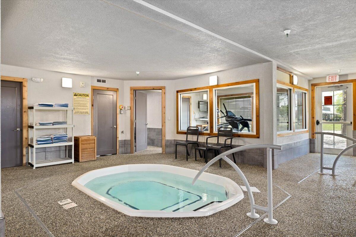 A pool area with a hot tub, seating, and a caution sign.