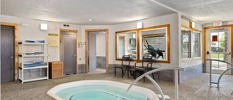 A pool area with a hot tub, seating, and a caution sign.