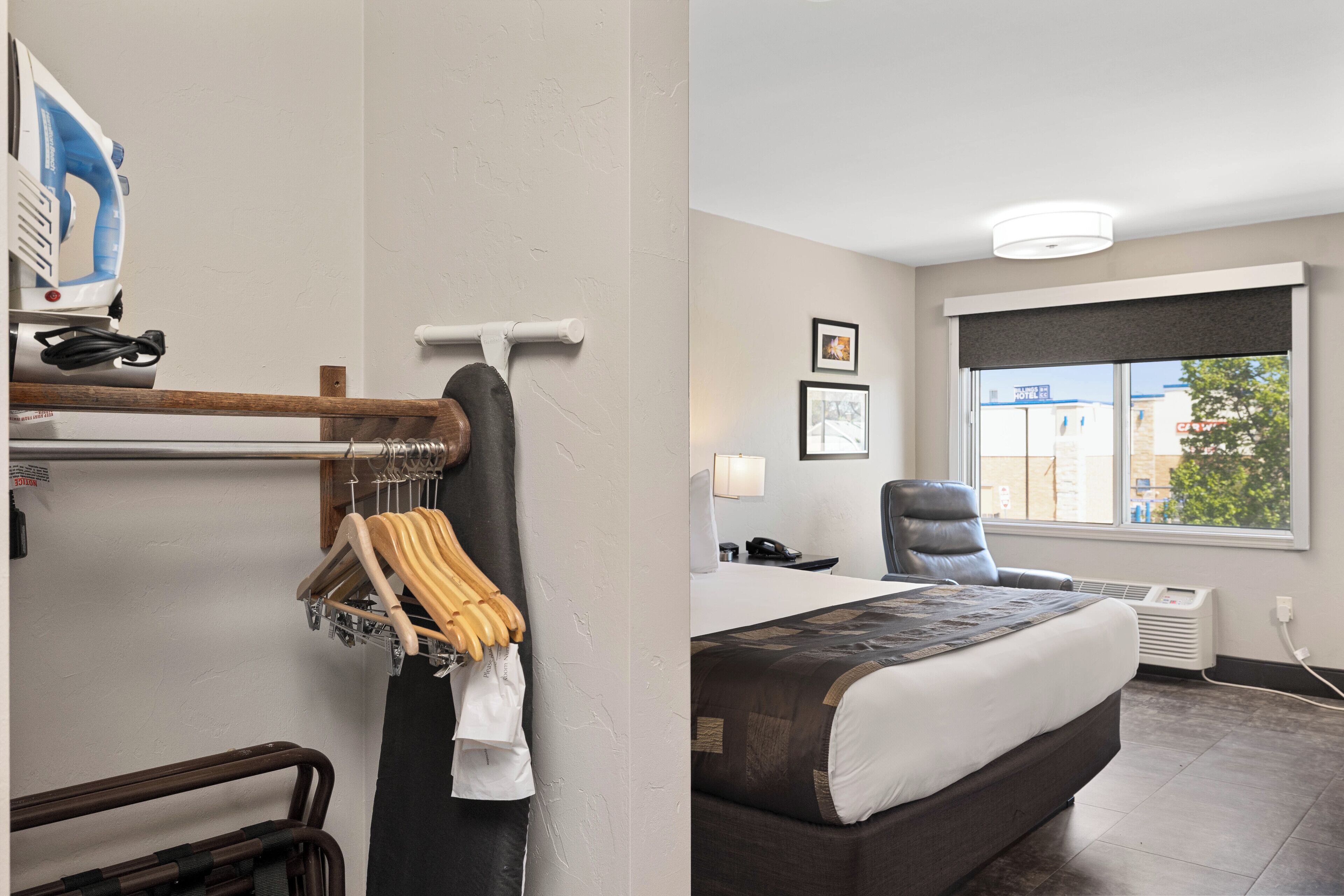 Une chambre d’hôtel avec un lit, une chaise, un bureau et une fenêtre donnant sur un paysage agréable.