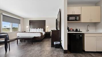 A hotel room with a bed, bedside table, lamp, and a view of the outdoors.