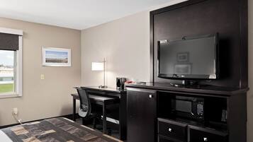 Une chambre d’hôtel comprenant un lit, un bureau avec une chaise, une télévision, un four à micro-ondes et un petit réfrigérateur.